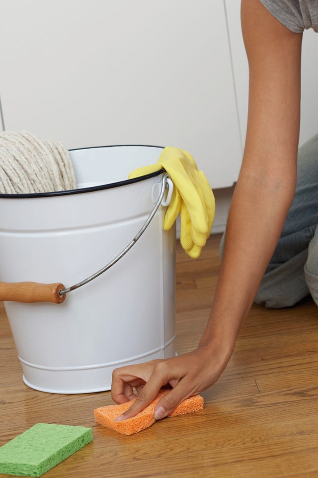 young woman kneeling to clean floor, smiling